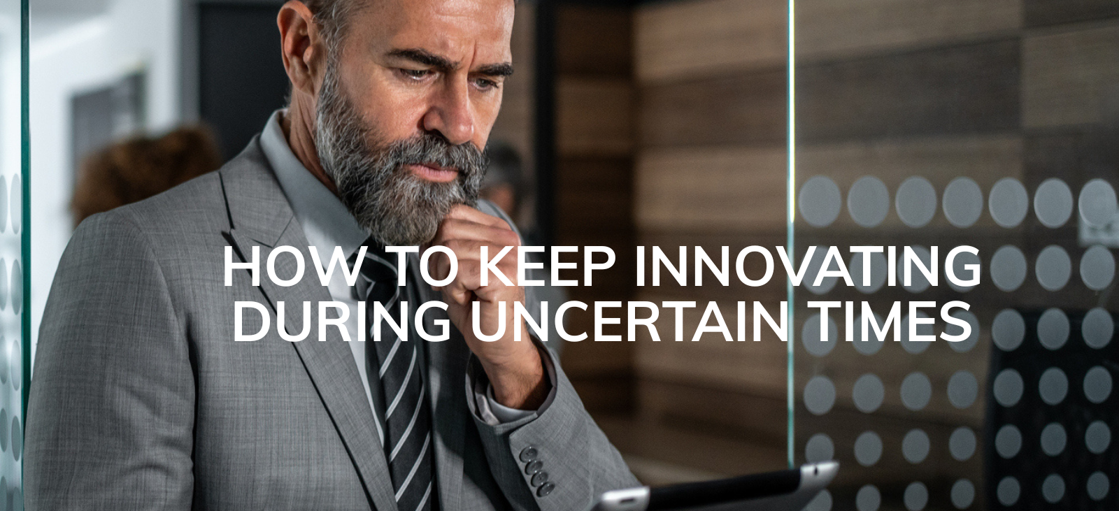 A bearded man in a suit look pensively